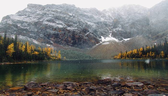 An image of a mountain lake with snow falling to remind people to practice gratitude during life's changes.