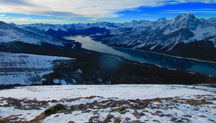 A photo taken on the risk taking hike to Mount Sparrowhawk and Read's Tower looking down on the Spray Lakes Reservoir in Kananaskis, Alberta, Canada. Someone was also risk taking by skating on the frozen reservoir below.