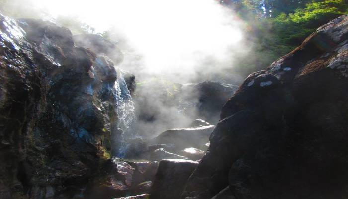 A photo of the 109C Hot Springs Cover, Vancouver Island, BC with steam coming off the rocks, a good method for self-care.