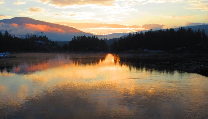 A photo of a meditation in nature, with a sunset in Nelson, BC, Canada. Includes mountains, lake, and the setting sun reflecting off the lake to instil a feeling of peace.