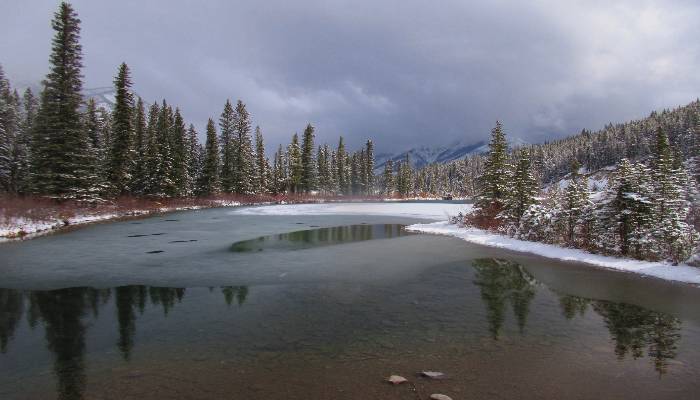 A photo of a snowy, rainy, sunshine mountain scene, with a pond reflecting the conditions. Our negative thoughts are reflected back to us, so we need to work on shifting them to something more positive.