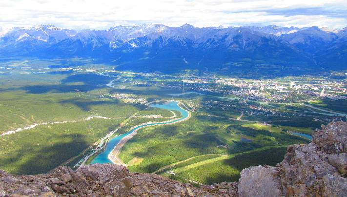 A photo from the top of Ha Ling Peak, Canmore, Alberta, Canada, looking down on the town from a scary height over the edge of a cliff. Learn how to stop worrying by feeling through your fear here.