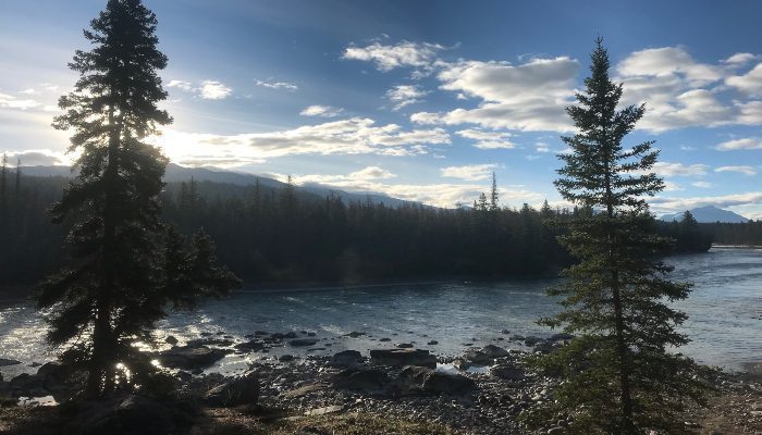 A photo of a peaceful scene at Jasper, Alberta, Canada with trees, river, clouds, blue sky, and sunshine. A great place to feel the the essence of time, and has a calming effect on crazy schedules. These are ways to manage your time.