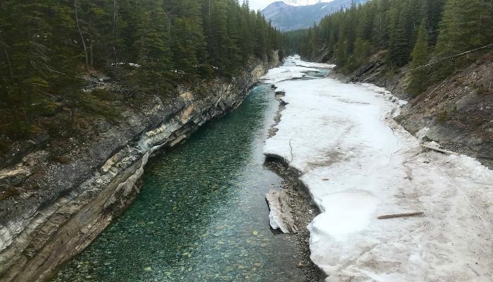 A photo of Stewart Canyon, Banff, Alberta, Canada with half ice, half running river like the state of our minds and hearts and we can learn mindfulness in nature here.