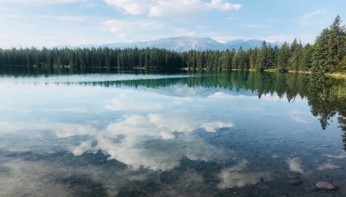 A photo of clouds reflecting off a still Lake Annette, Jasper, Alberta, Canada, like the cloudy thoughts in our minds when taking things personally.