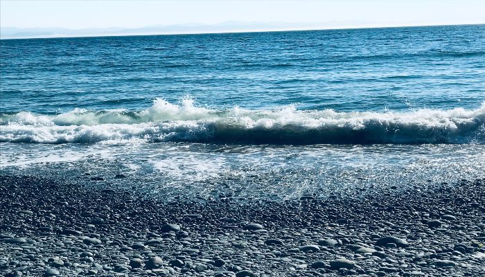 A photo of a large wave crashing onto the shore at French Beach, Vancouver Island, a beautiful way to learn how to raise your energy vibration.